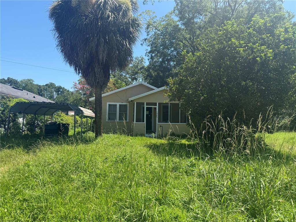 A single-story house with a screened porch stands behind a tall, overgrown grassy yard — 5905 BRILEY AVENUE, JACKSONVILLE, FL
