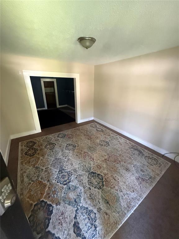A room with beige walls, brown carpet, a patterned area rug, and a doorway leading inside — 5905 BRILEY AVENUE, JACKSONVILLE, FL