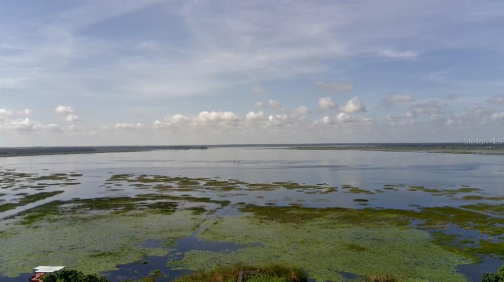 An aerial view shows a large lake with patches of vegetation and a small dock — 502 CANAL DRIVE, LAKE WALES, FL