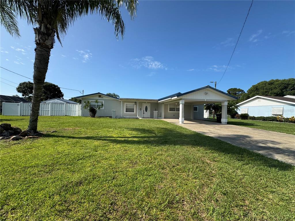 A single-story house with a carport and a large front lawn under a blue sky — 502 CANAL DRIVE, LAKE WALES, FL