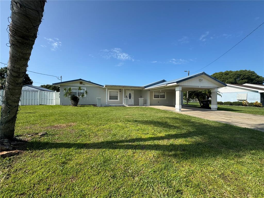 A single-story house with a light-colored exterior, a front carport, and a grassy lawn — 502 CANAL DRIVE, LAKE WALES, FL
