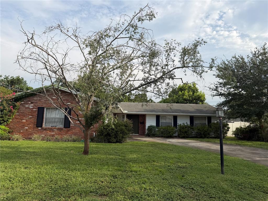 A single-story brick and white siding house features a large, bare tree in the front yard — 2124 MISCINDY PLACE, ORLANDO, FL