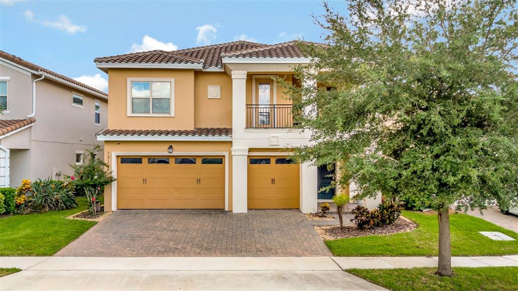 A two-story house with a tan stucco exterior, a three-car garage, and a paved driveway — 13109 STANTHORNE AVENUE, ORLANDO, FL