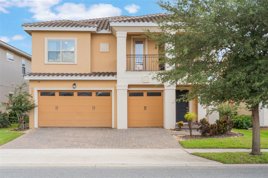 A two-story house with a tan stucco exterior, two garage doors, and a second-floor balcony — 13109 STANTHORNE AVENUE, ORLANDO, FL