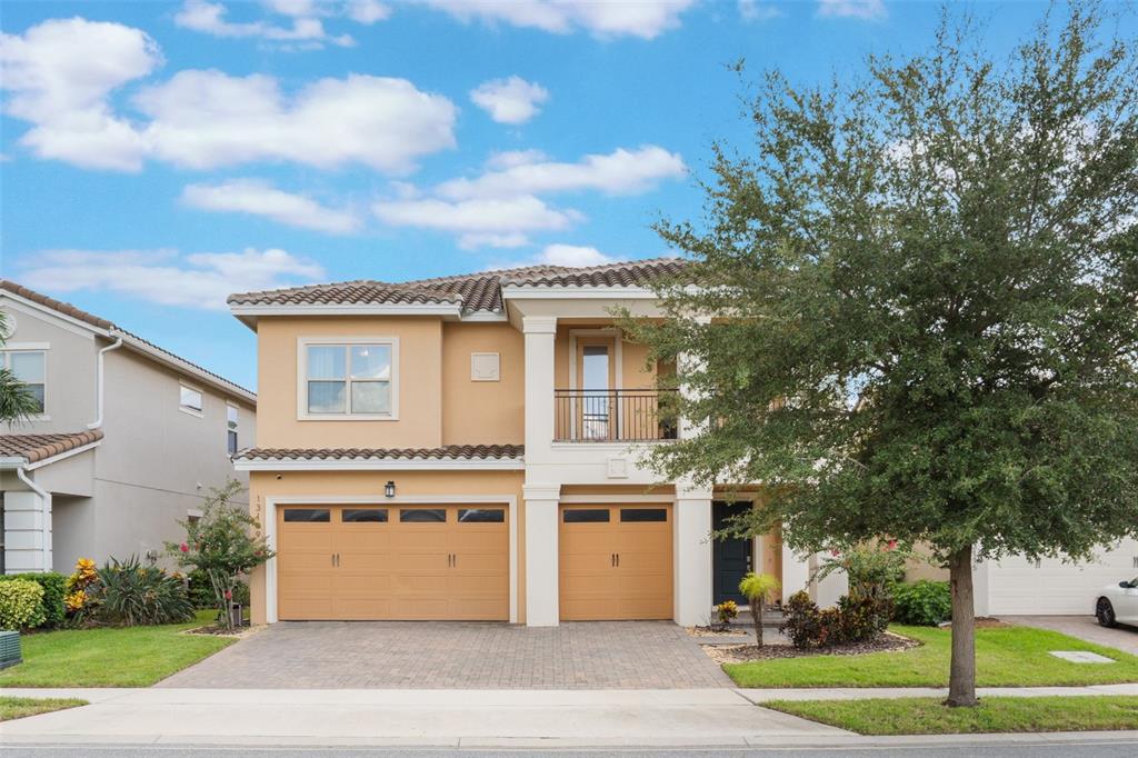 A two-story tan house with a two-car garage, a balcony, and a paved driveway — 13109 STANTHORNE AVENUE, ORLANDO, FL