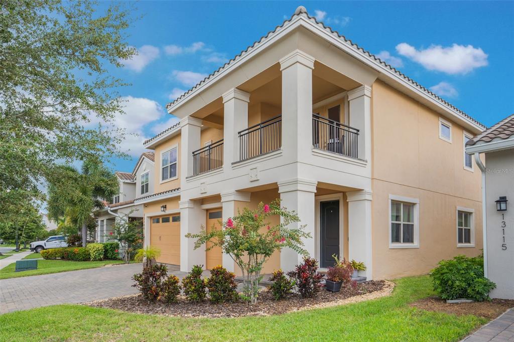 A two-story stucco townhouse features a covered balcony, a two-car garage, and a landscaped yard — 13109 STANTHORNE AVENUE, ORLANDO, FL