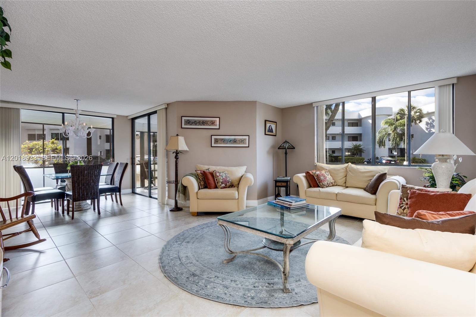 A living room with tile floors, a glass coffee table, and a dining area nearby — 1410 Sheridan St # 9I, Hollywood FL 33020, HOLLYWOOD, FL