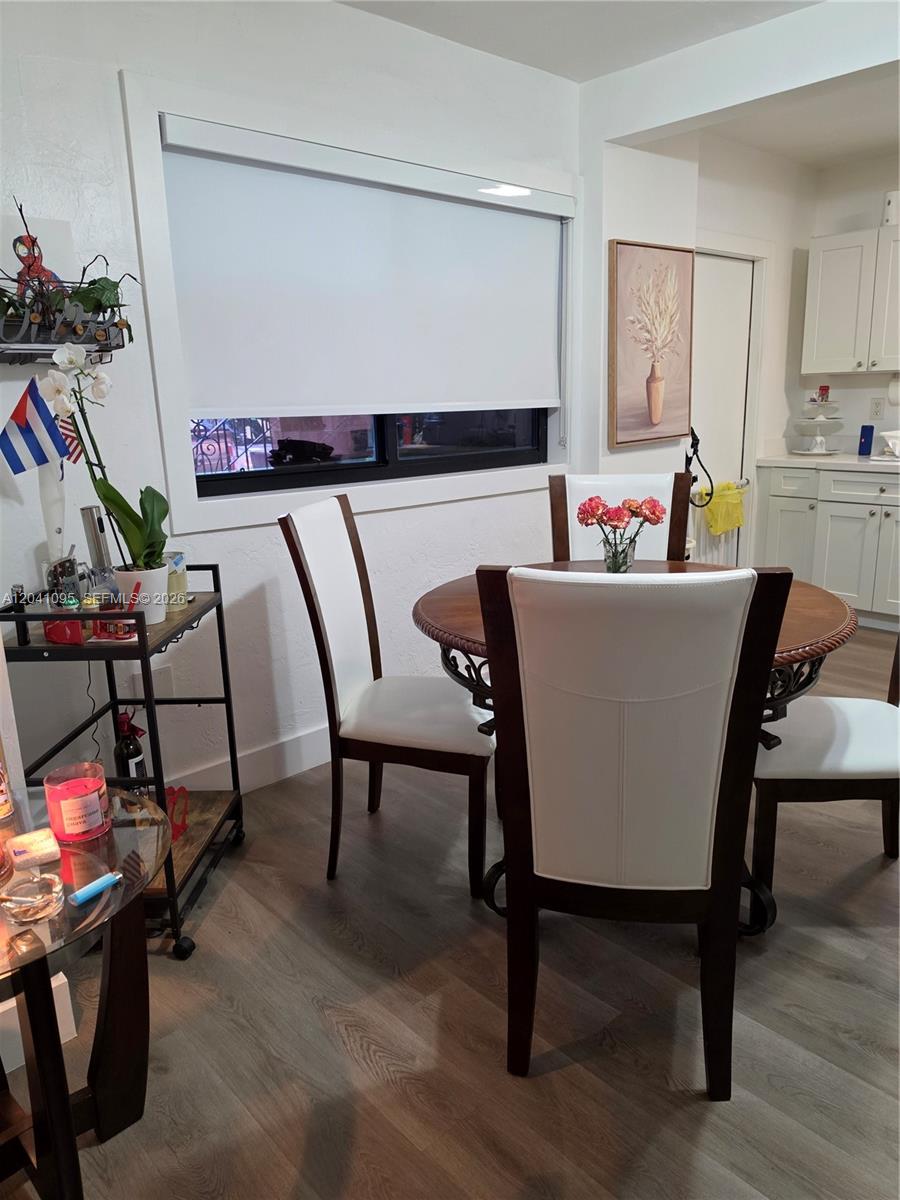 A dining area features a round wooden table, white chairs, and a window with blinds — 711 Beacom Blvd # 4, Miami FL 33135, MIAMI, FL