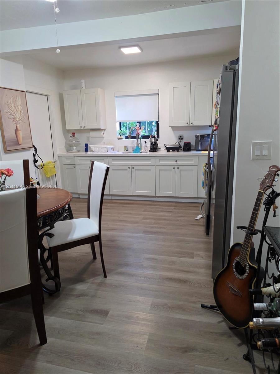 A kitchen features white cabinets, light wood-look flooring, and a dining area with chairs — 711 Beacom Blvd # 4, Miami FL 33135, MIAMI, FL