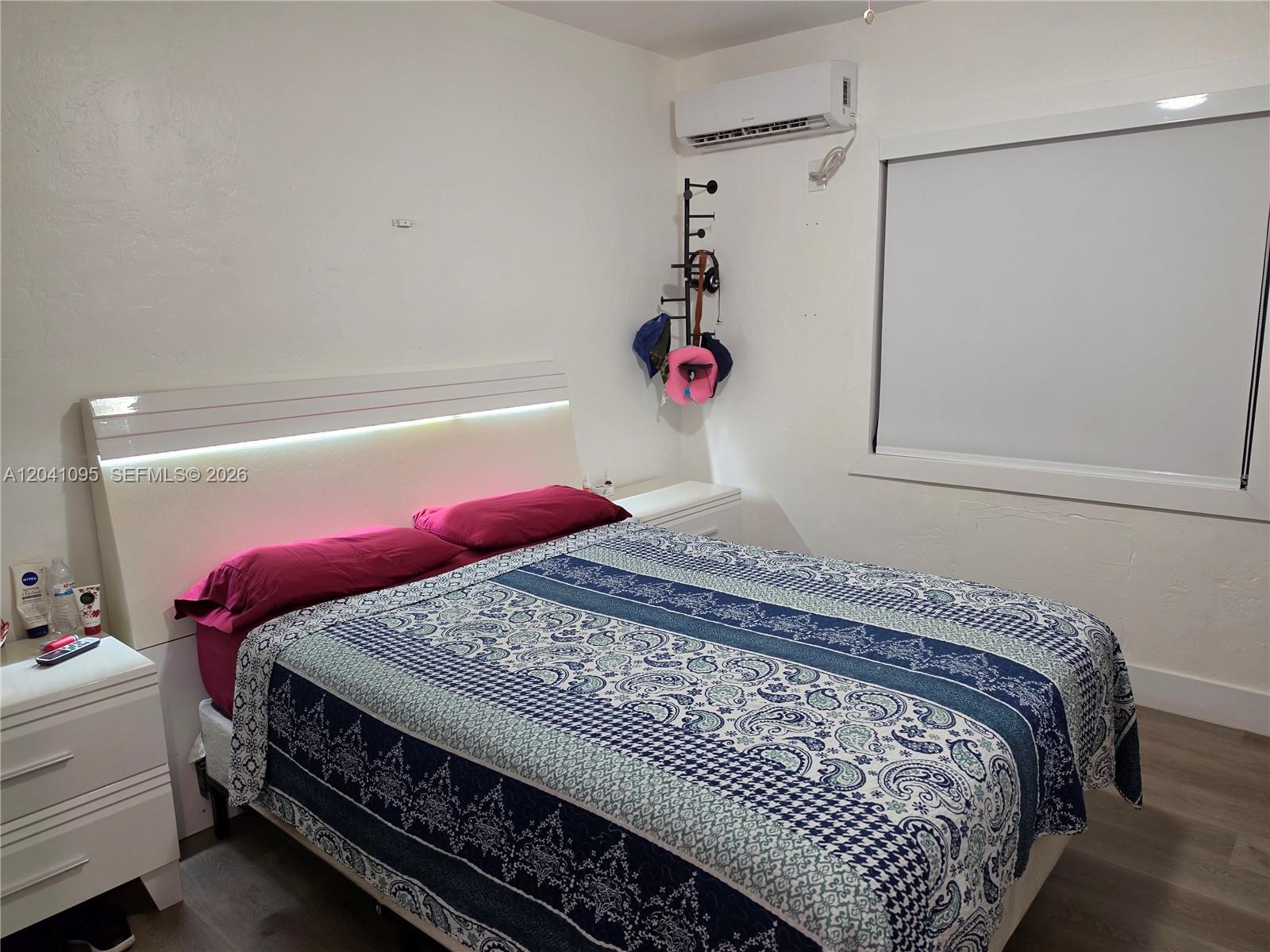 A bedroom features a bed with a patterned comforter, a white headboard, and a wall-mounted AC — 711 Beacom Blvd # 4, Miami FL 33135, MIAMI, FL