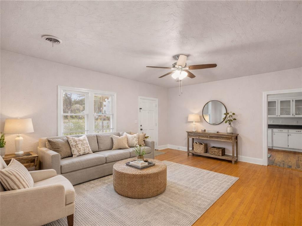 A living room features a gray sofa, a round woven coffee table, and hardwood floors — 5915 AVENUE F, MC INTOSH, FL