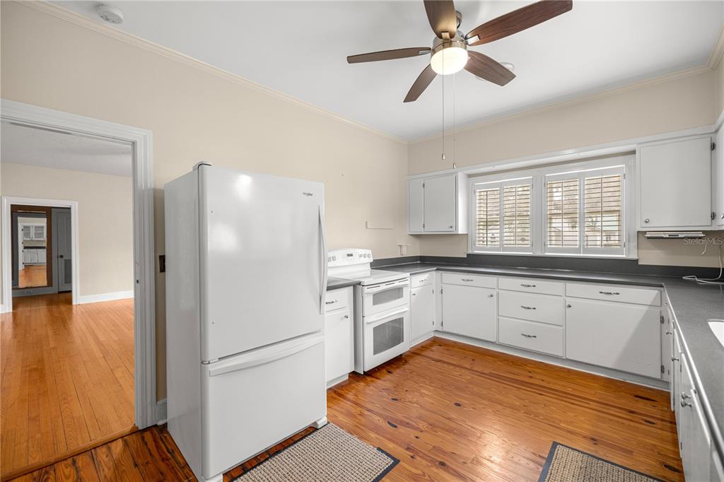 A kitchen features white cabinets, a white refrigerator, a white stove, and hardwood flooring — 5915 AVENUE F, MC INTOSH, FL