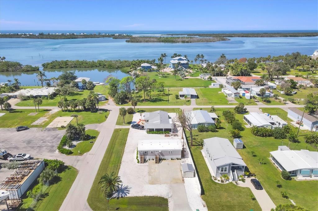 An aerial view shows a coastal neighborhood with houses, palm trees, and a nearby waterway — 3280 HOLLY AVENUE, ENGLEWOOD, FL