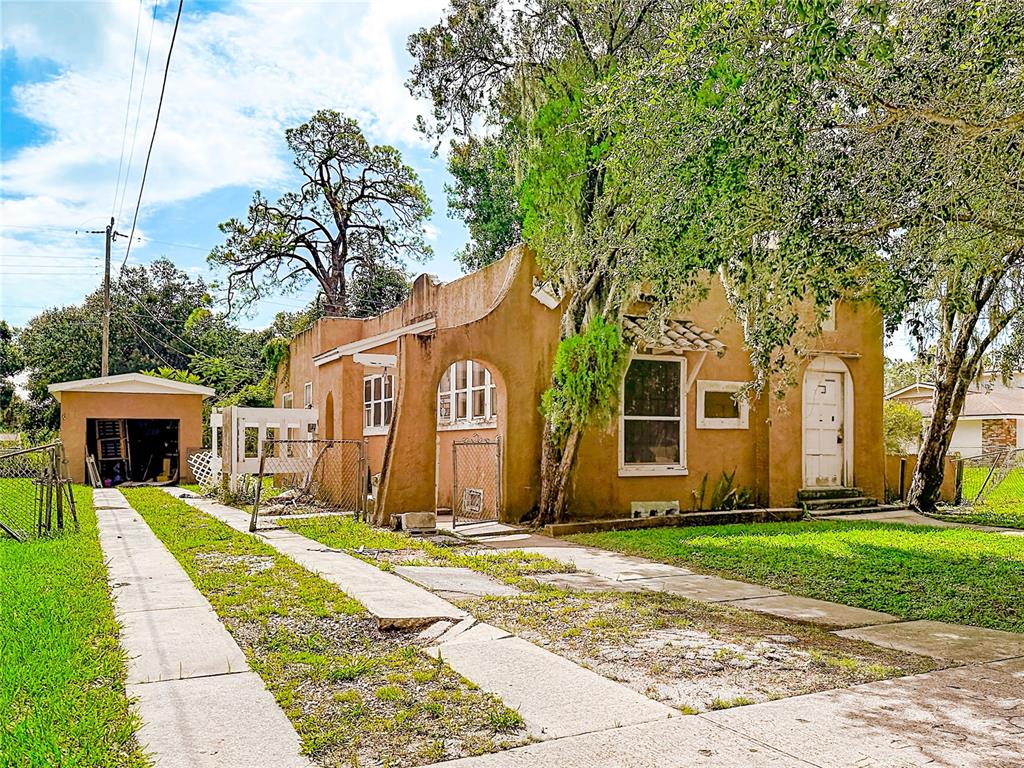 A tan stucco house with a detached garage and a driveway under large trees — 618 S VARR AVENUE, COCOA, FL