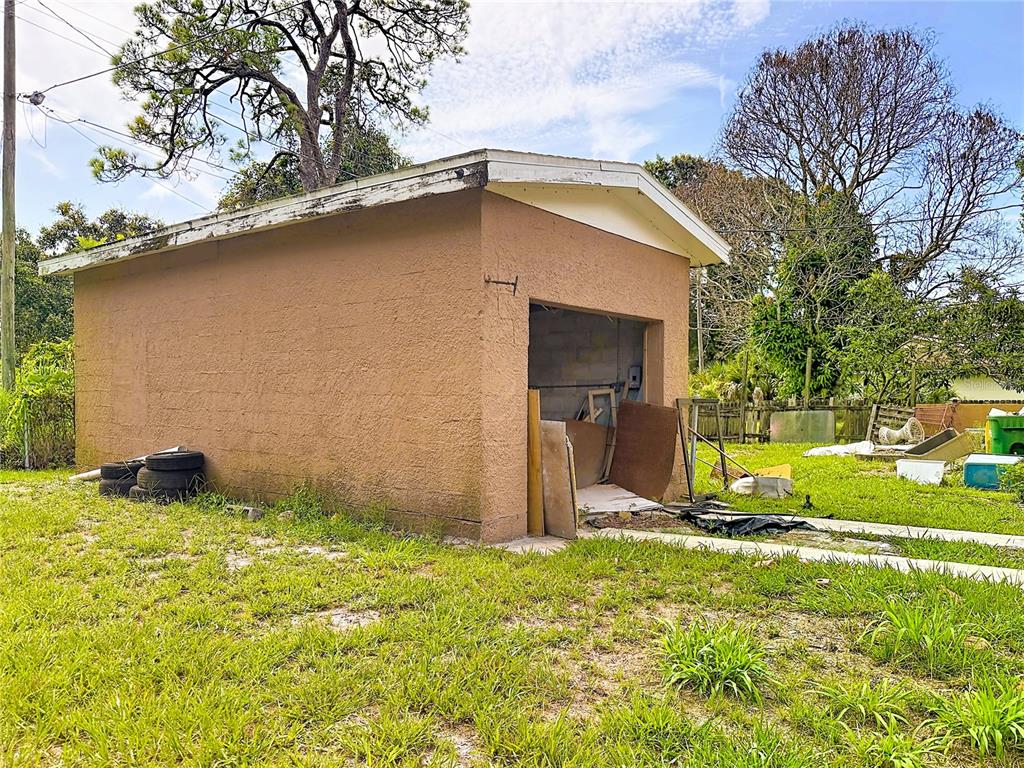 A detached, stucco-finished garage with an open bay sits on a grassy lot — 618 S VARR AVENUE, COCOA, FL
