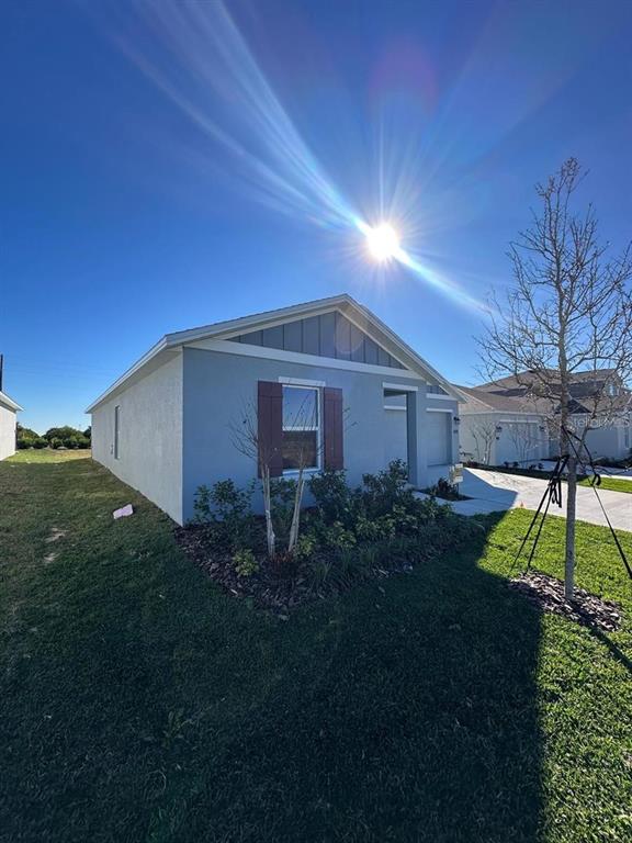 A single-story house with blue stucco siding and brown shutters under a bright sun — 2822 PENNACHIO DRIVE, LAKE WALES, FL