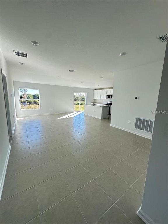 An open-concept living area features light tile flooring, recessed lighting, and a kitchen with white cabinetry — 2822 PENNACHIO DRIVE, LAKE WALES, FL