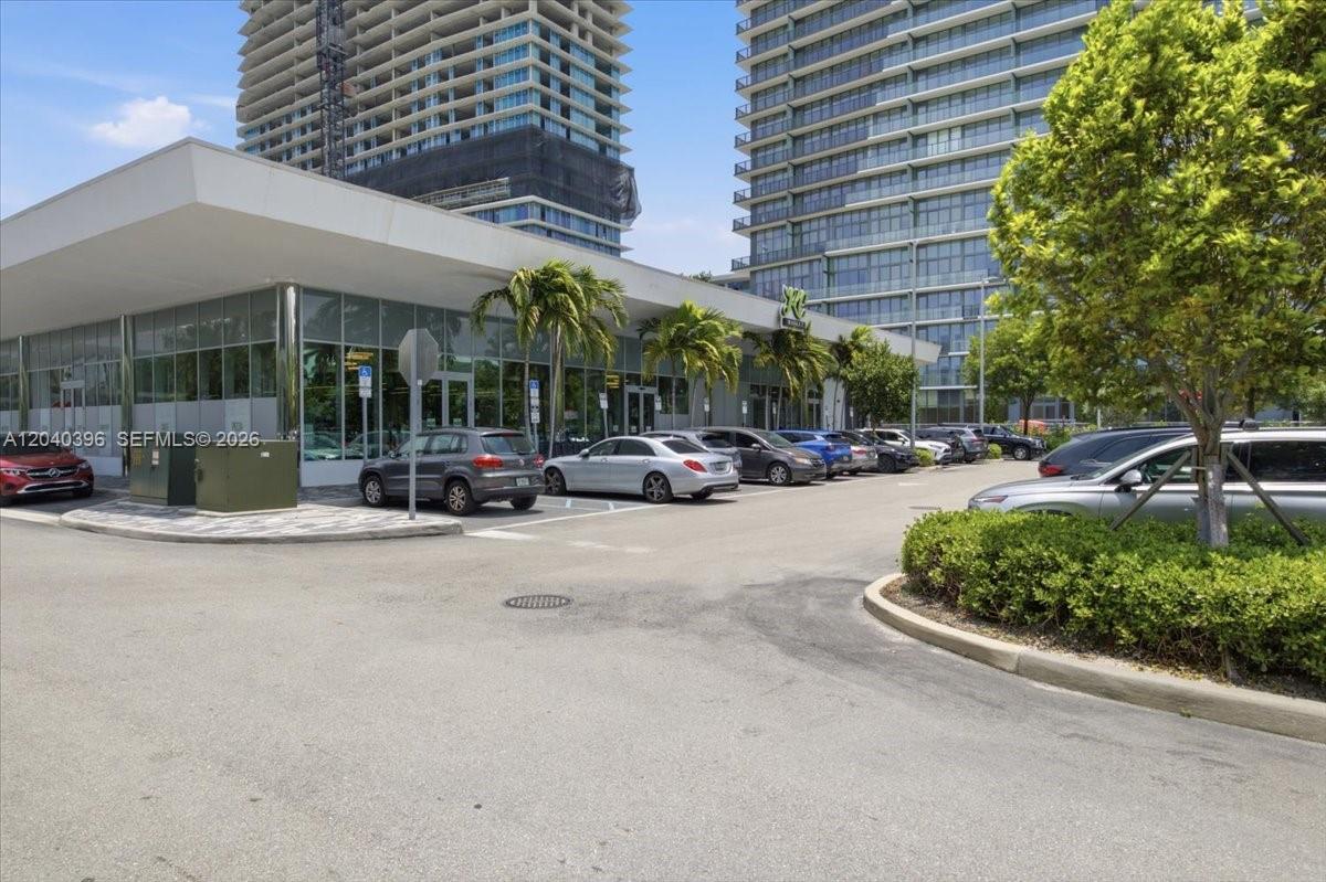 A low-rise commercial building with glass walls sits in front of two tall residential towers — 1002 E Hallandale Beach Blvd # 101, Hallandale Beach FL 33009, HALLANDALE BEACH, FL