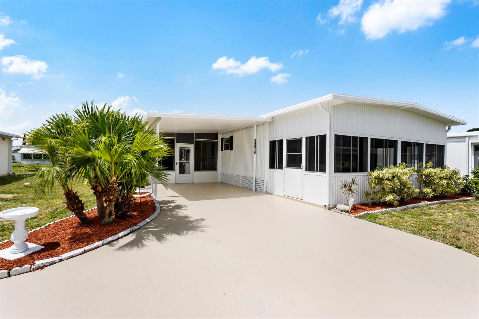A white mobile home features a screened-in porch, a carport, and a palm tree — 39016 Gayle Bay, Boynton Beach FL 33436, BOYNTON BEACH, FL