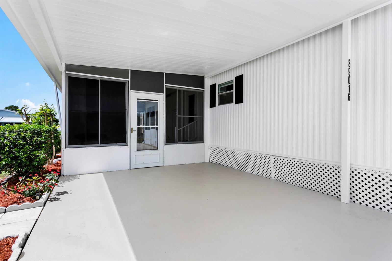 A covered concrete patio features white lattice skirting, a screen enclosure, and a white door — 39016 Gayle Bay, Boynton Beach FL 33436, BOYNTON BEACH, FL