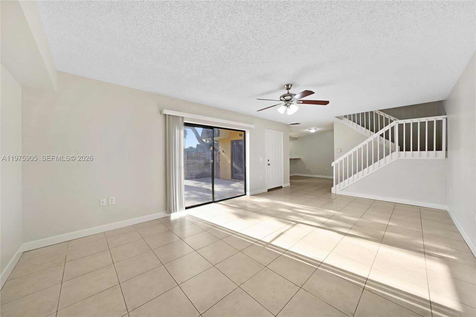 A living room with tile floors, a ceiling fan, sliding glass doors, and a staircase — 2206 22nd Way, West Palm Beach FL 33407, WEST PALM BEACH, FL