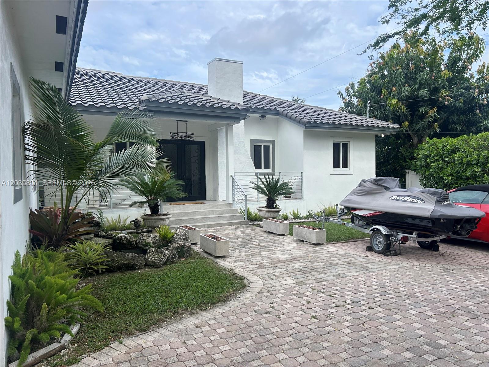 A white house with a tiled roof, paved driveway, and a jet ski on a trailer — 12885 SW 77 AVE, Pinecrest FL 33156, PINECREST, FL