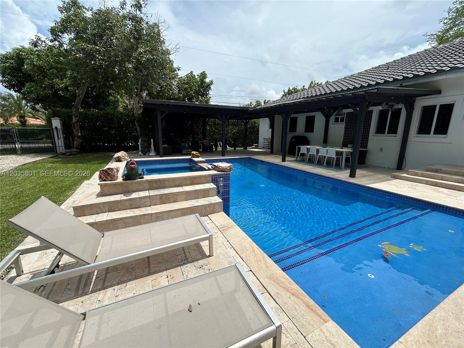 A backyard features a rectangular swimming pool with an attached spa and a covered patio — 12885 SW 77 AVE, Pinecrest FL 33156, PINECREST, FL