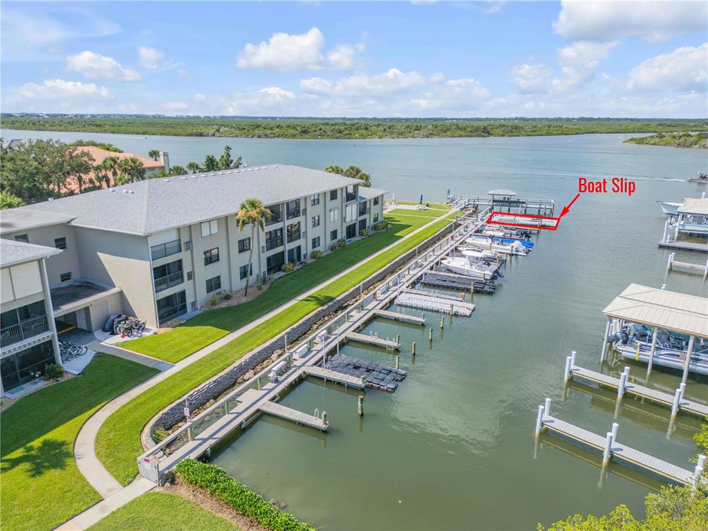 An aerial view shows a multi-story apartment building next to a private boat dock — 2100 N PENINSULA AVENUE UNIT 305, NEW SMYRNA BEACH, FL