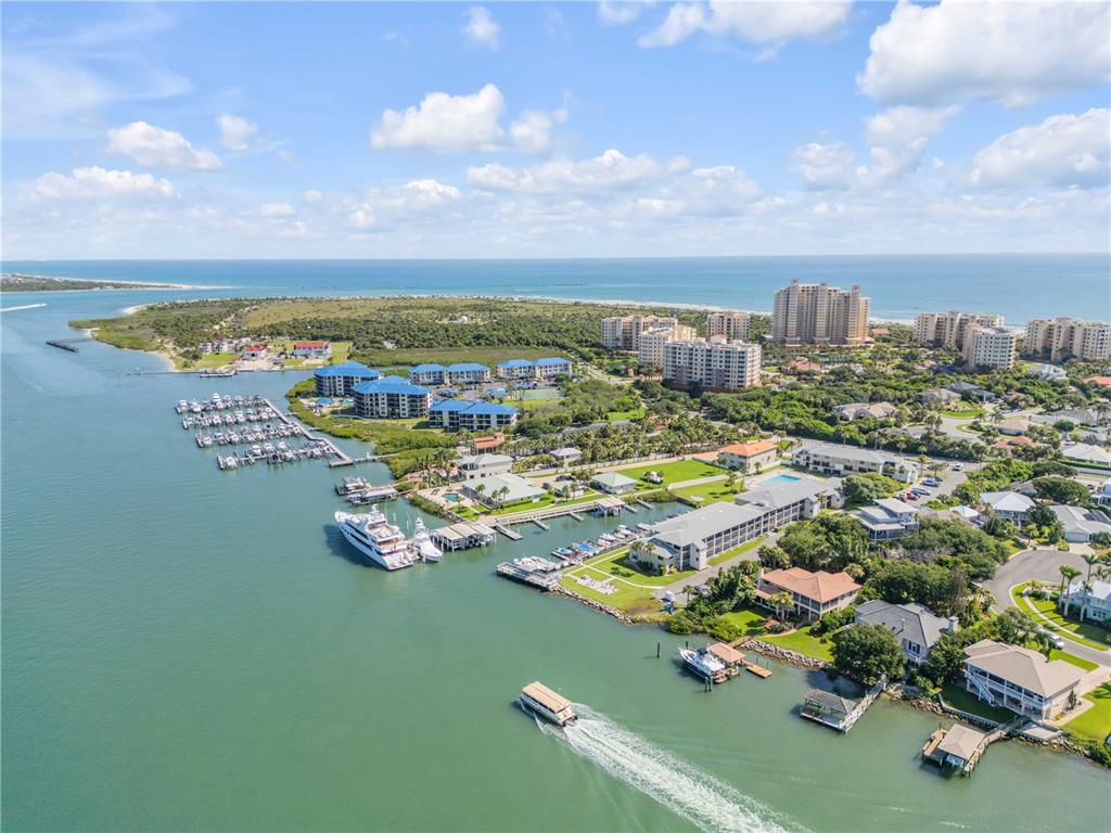 An aerial view shows a marina, waterfront residential buildings, and a boat cruising on the water — 2100 N PENINSULA AVENUE UNIT 305, NEW SMYRNA BEACH, FL