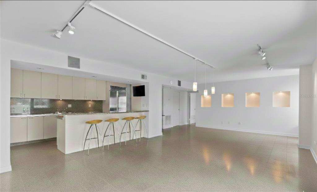 A modern kitchen with a breakfast bar and stools opens into a spacious, tiled living area — 2401 BAYSHORE BOULEVARD UNIT 410, TAMPA, FL