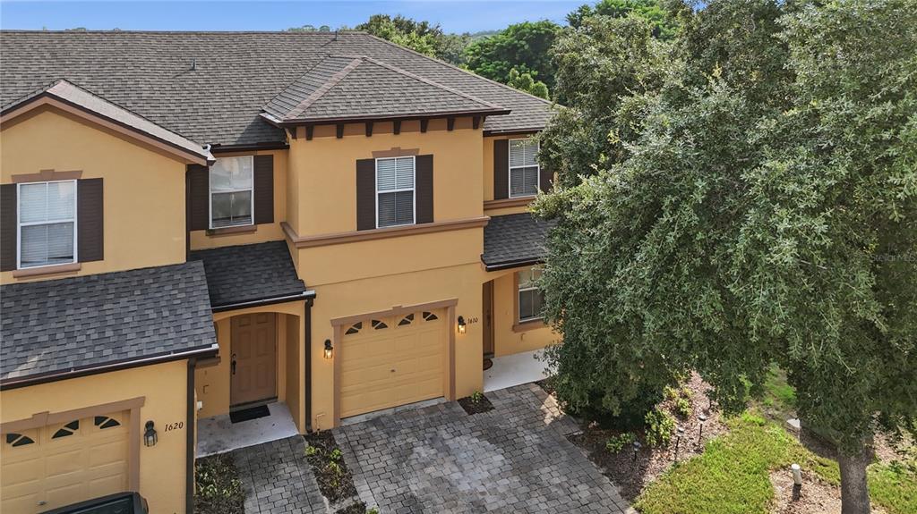 An aerial view shows the exterior of a two-story tan townhouse with a paved driveway — 1610 RETREAT VIEW CIRCLE, SANFORD, FL