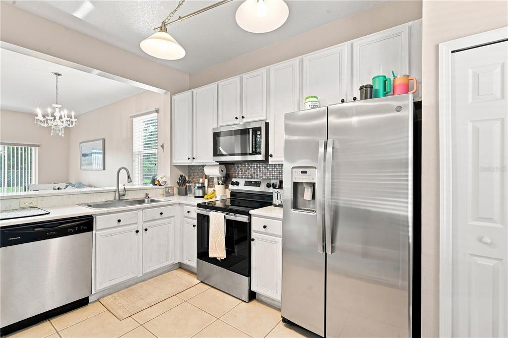 A kitchen with white cabinets, stainless steel appliances, and a tiled backsplash — 1610 RETREAT VIEW CIRCLE, SANFORD, FL