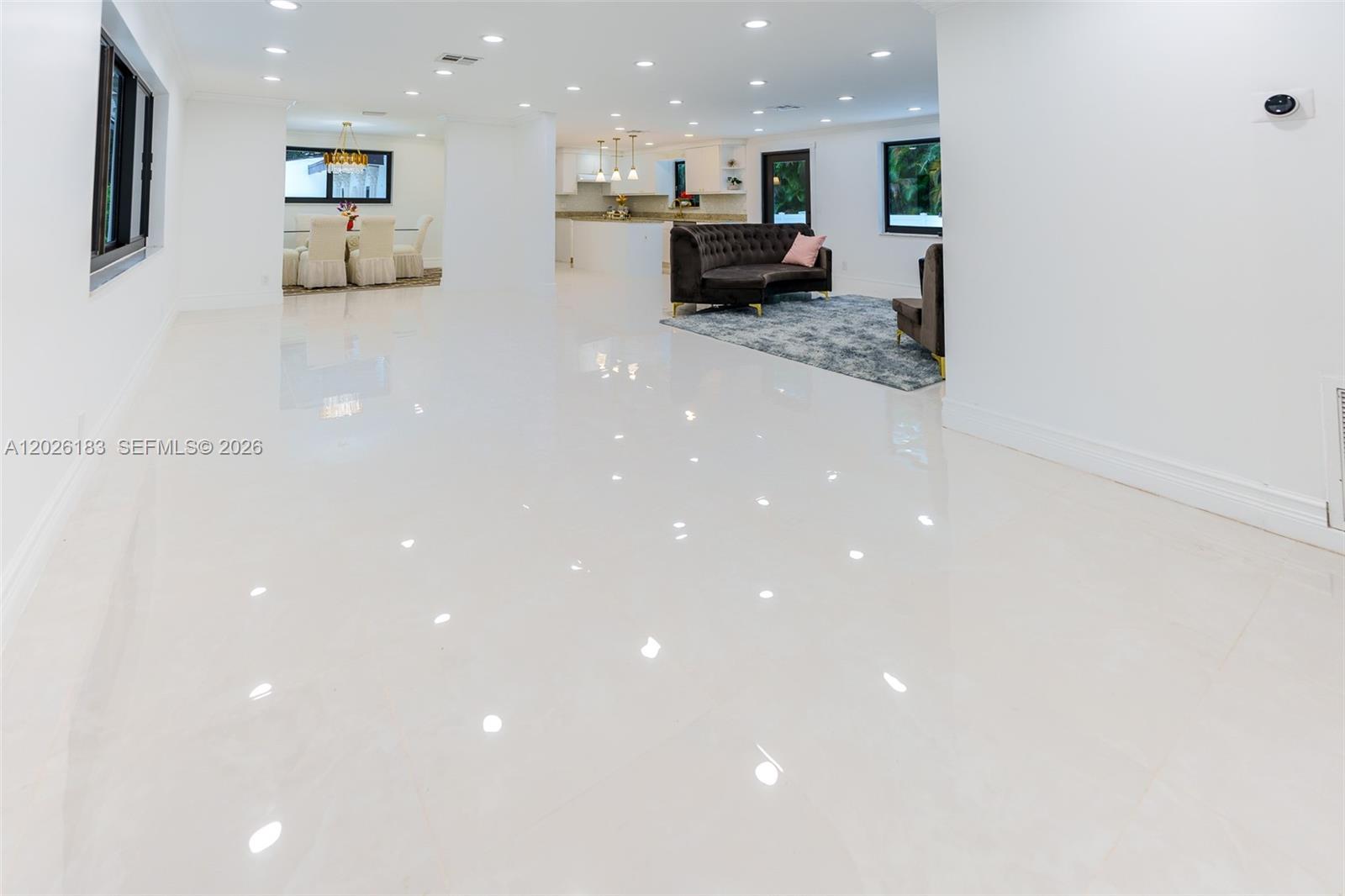 An open-concept living and dining area features white tile flooring and recessed ceiling lights — 12200 NW 20th Ct, Plantation FL 33323, PLANTATION, FL
