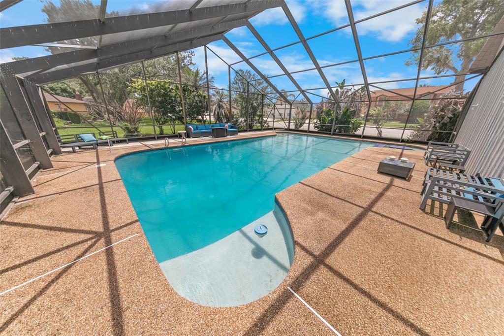A screened-in swimming pool with a textured concrete deck and outdoor furniture — 38 LAZY EIGHT DRIVE, PORT ORANGE, FL