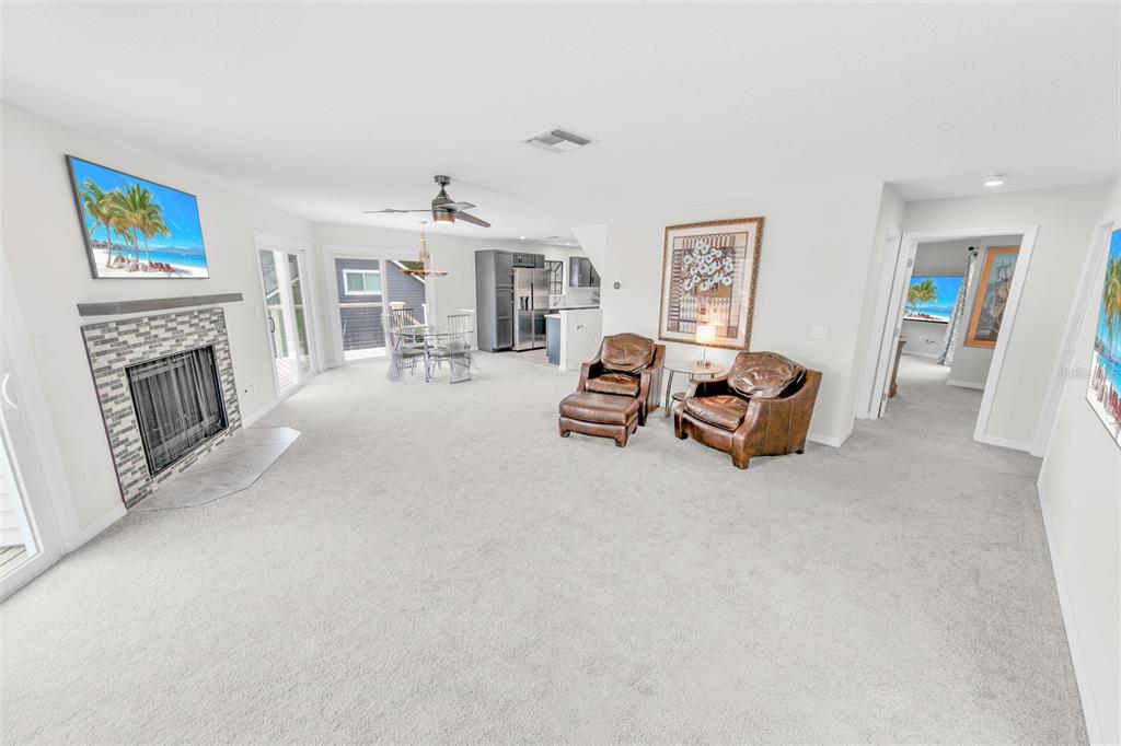 A carpeted living room features a fireplace, two leather armchairs, and an adjacent dining area — 38 LAZY EIGHT DRIVE, PORT ORANGE, FL