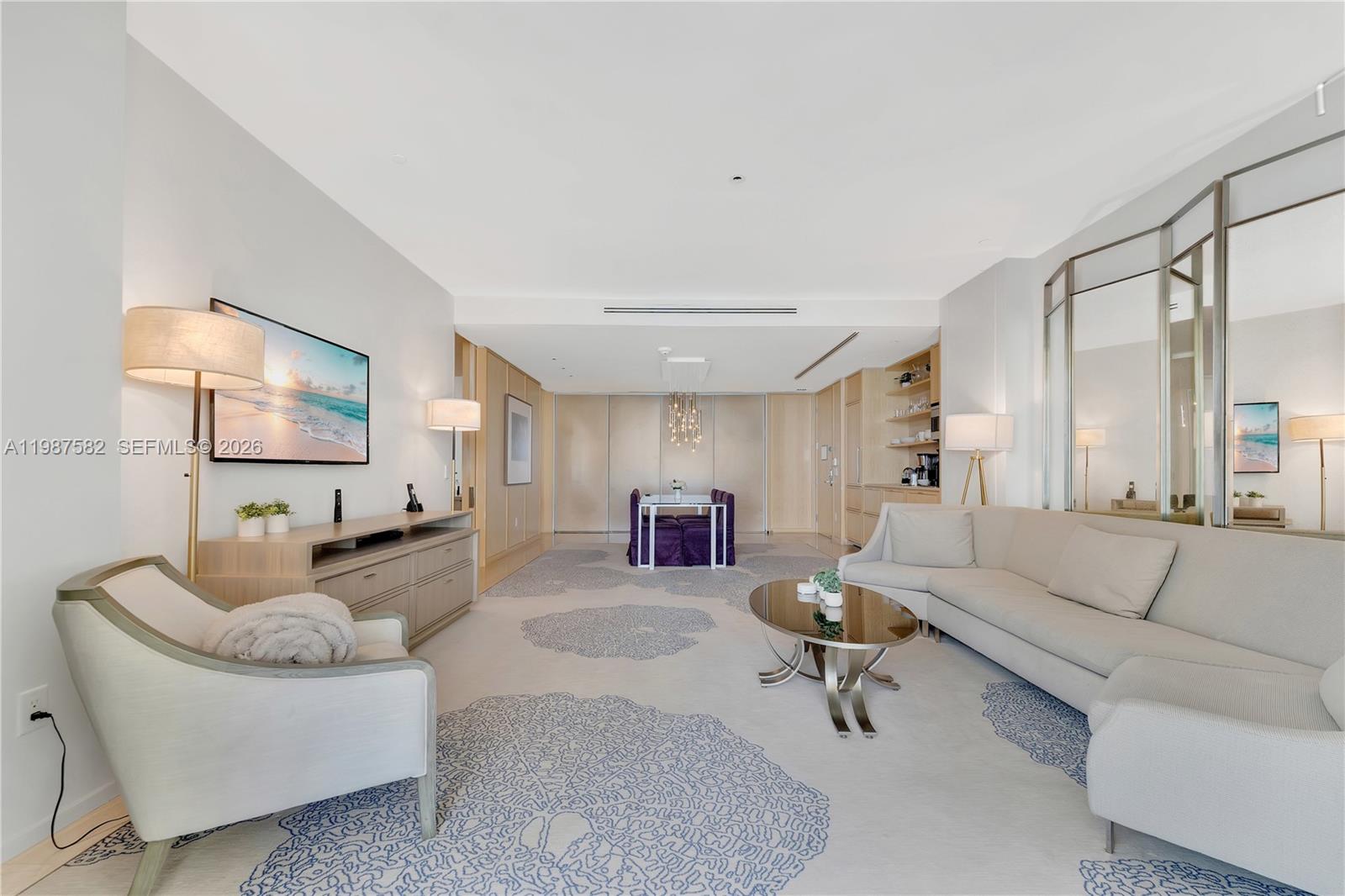 A modern living room features a light-colored sectional sofa, patterned area rug, and dining area — 9703 Collins Ave # 1006, Bal Harbour FL 33154, BAL HARBOUR, FL