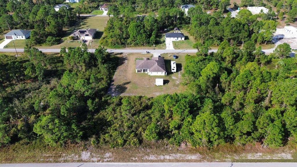 An aerial view shows a single-story house surrounded by trees and a large grassy yard — 710 RANDALL AVENUE E, LEHIGH ACRES, FL