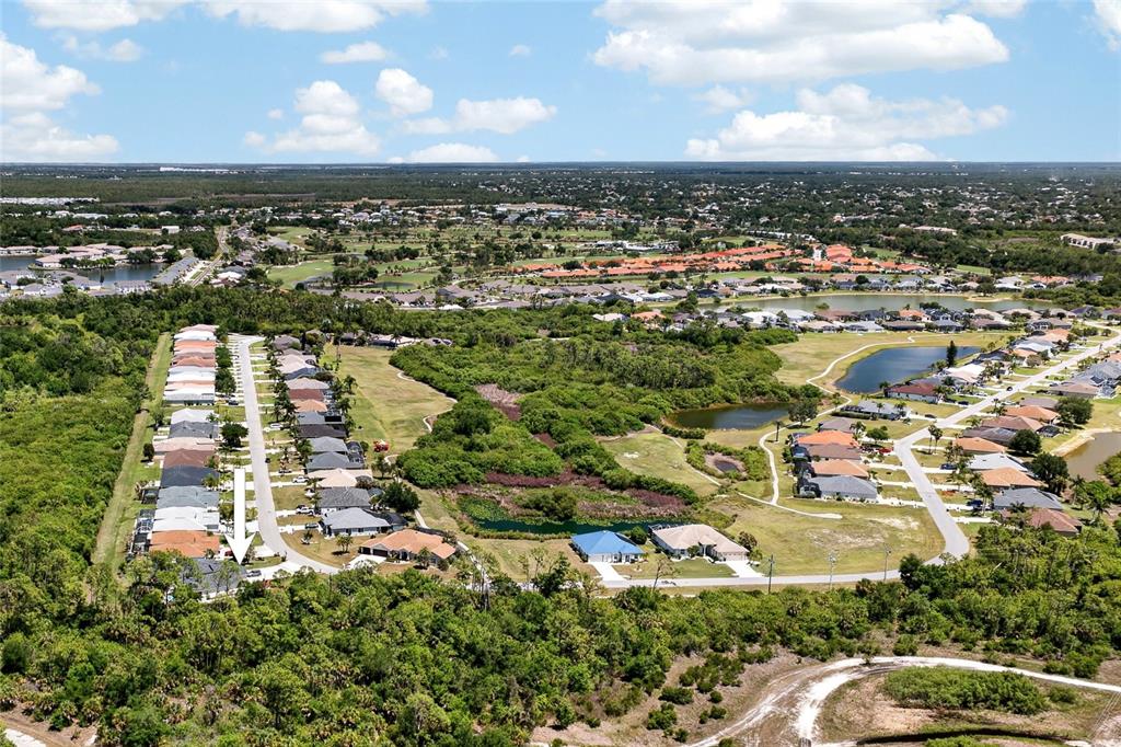 An aerial view shows a residential neighborhood with houses, ponds, and surrounding green space — 13440 SW PEMBROKE CIRCLE N, LAKE SUZY, FL