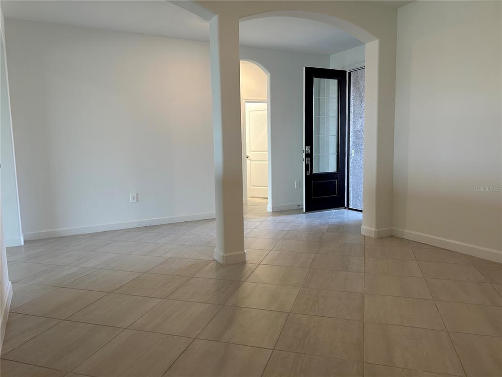 An interior view shows a tiled room with an arched entryway and a black front door — 15513 WHITE LINEN DRIVE, LAKEWOOD RANCH, FL