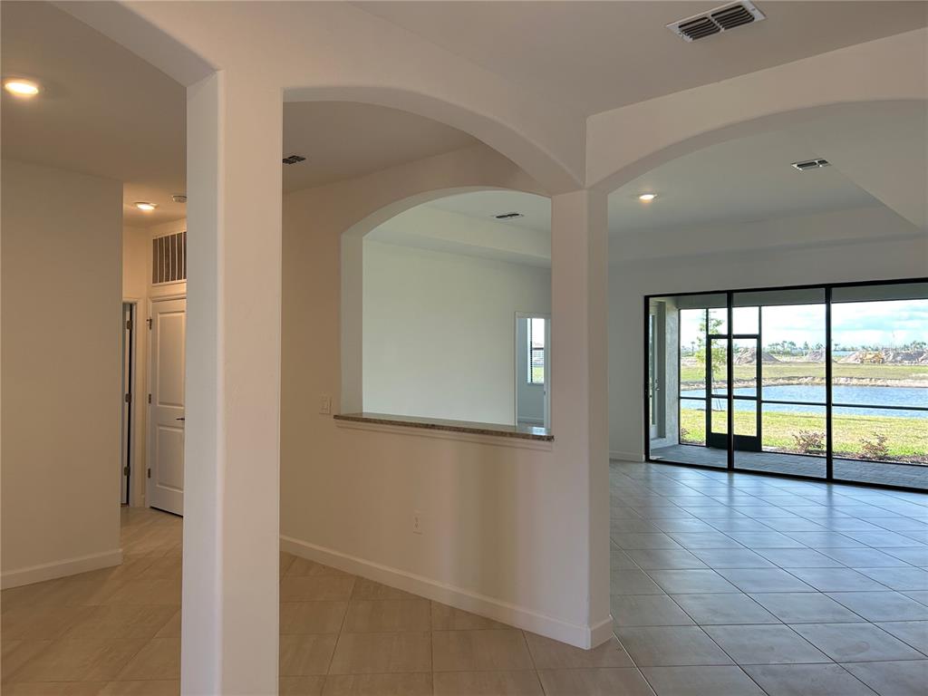 An interior view shows a tiled living area with arched openings and a lake view — 15513 WHITE LINEN DRIVE, LAKEWOOD RANCH, FL