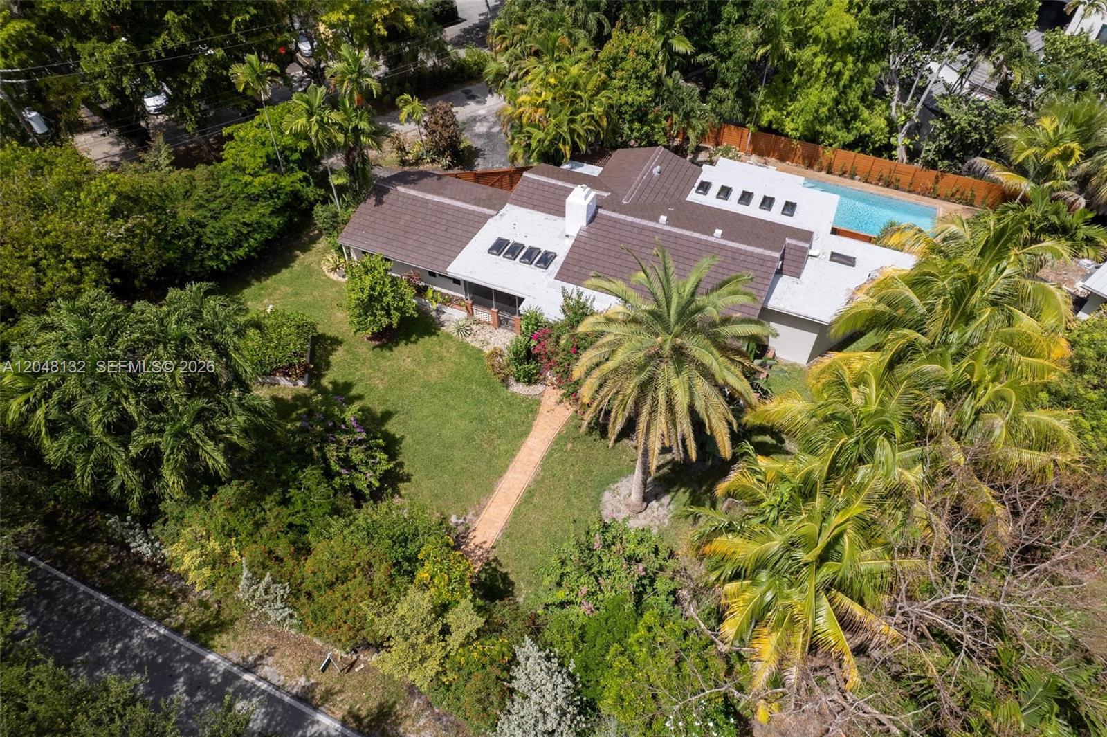 An aerial view shows a house with a brown roof, pool, and lush landscaping — 12045 Griffing Blvd, Biscayne Park FL 33161, BISCAYNE PARK, FL