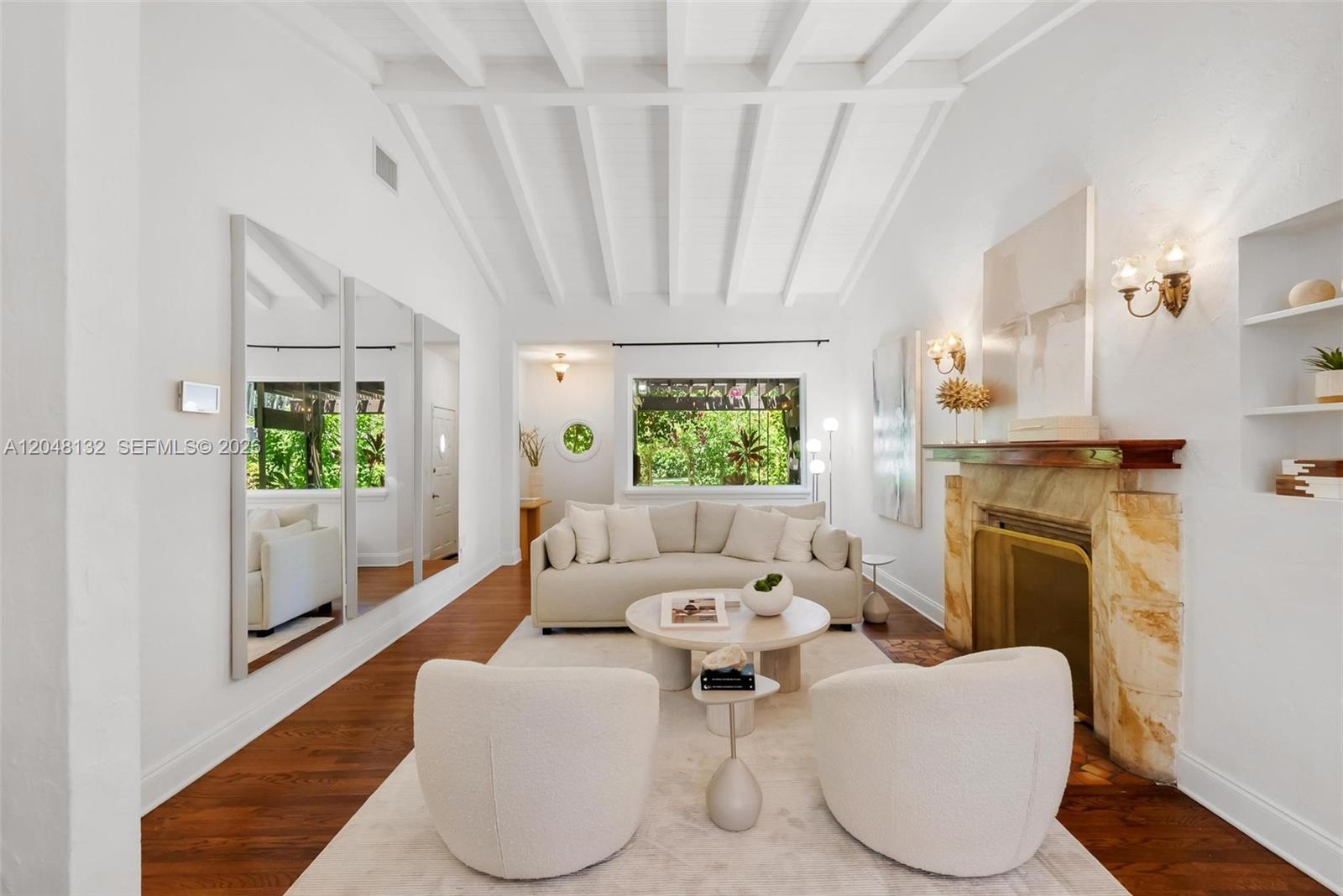 A living room features a vaulted beamed ceiling, a stone fireplace, and white furniture — 12045 Griffing Blvd, Biscayne Park FL 33161, BISCAYNE PARK, FL