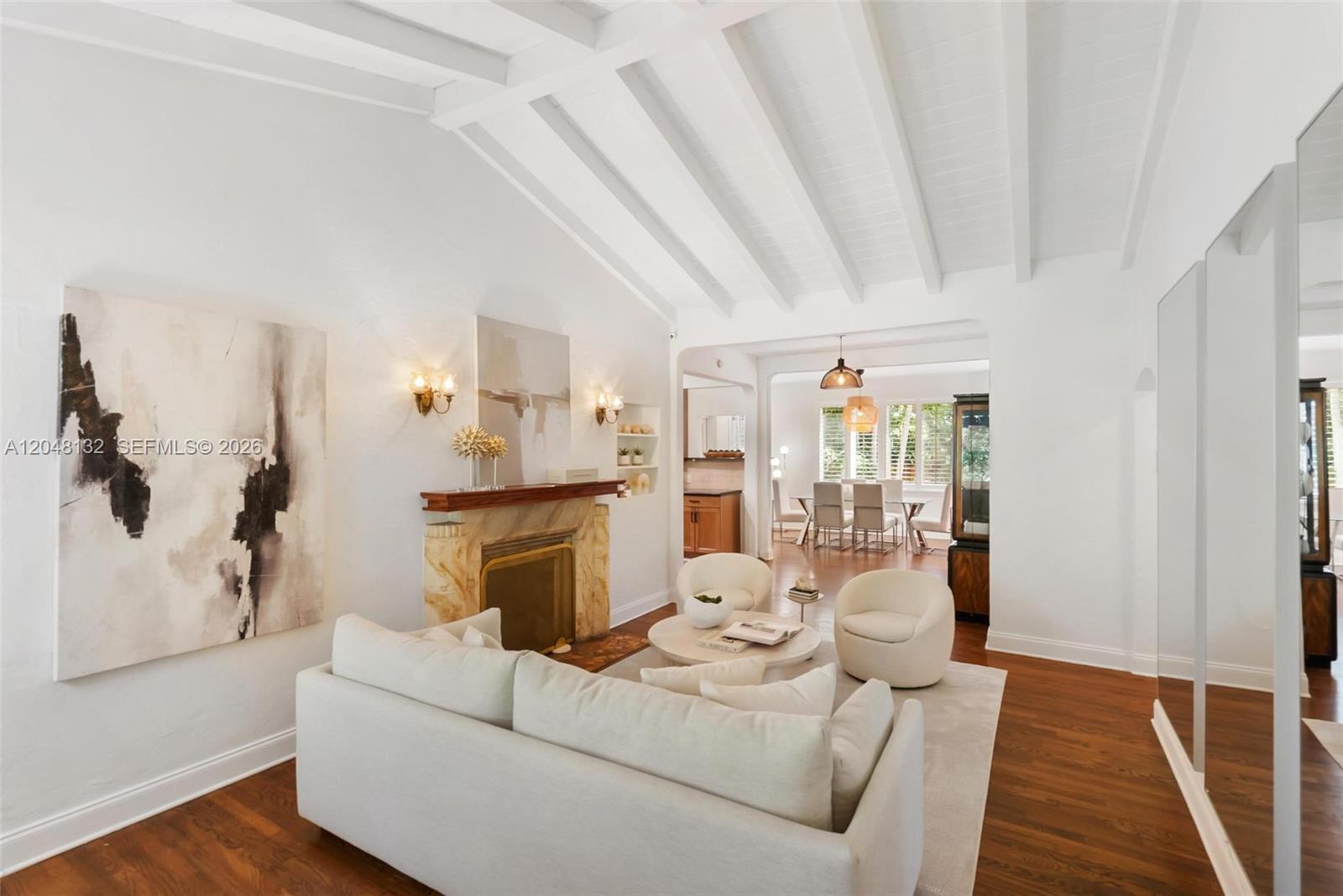 A living room features a fireplace, white vaulted beamed ceilings, and hardwood floors — 12045 Griffing Blvd, Biscayne Park FL 33161, BISCAYNE PARK, FL