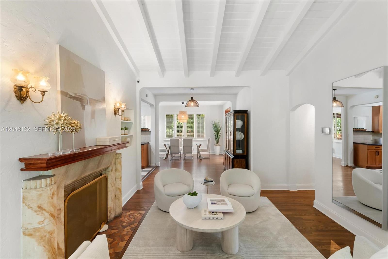 A living room features a stone fireplace, white barrel-vaulted ceilings, and a dining area beyond — 12045 Griffing Blvd, Biscayne Park FL 33161, BISCAYNE PARK, FL