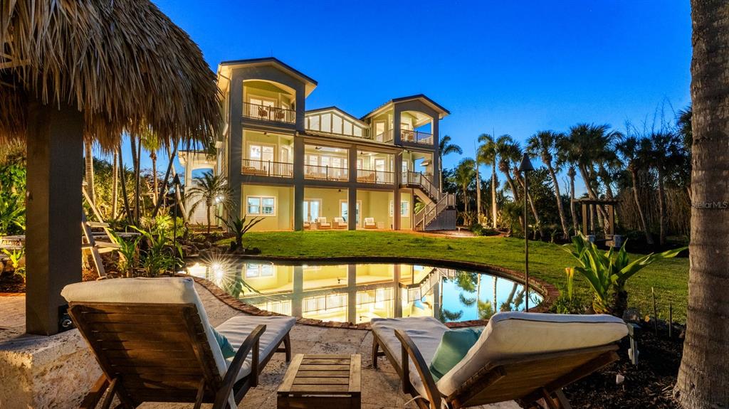A multi-story house with a pool and lounge chairs in the foreground at dusk — 10460 SUNNY DREAMS TERRACE, PLACIDA, FL