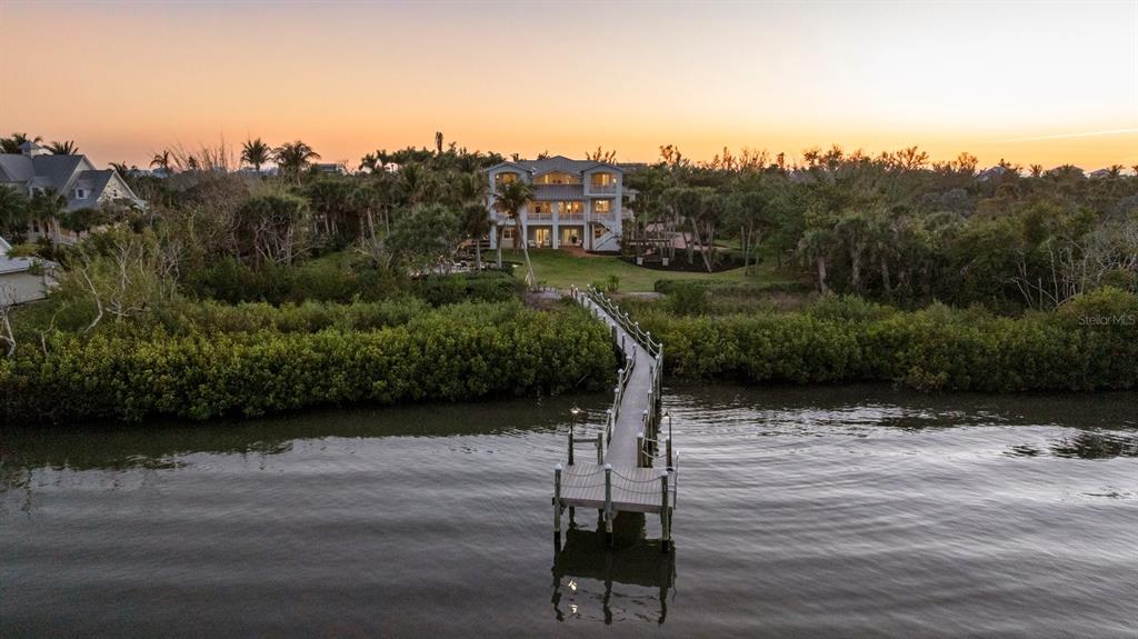 An aerial view shows a multi-story house with a long wooden dock extending into water — 10460 SUNNY DREAMS TERRACE, PLACIDA, FL