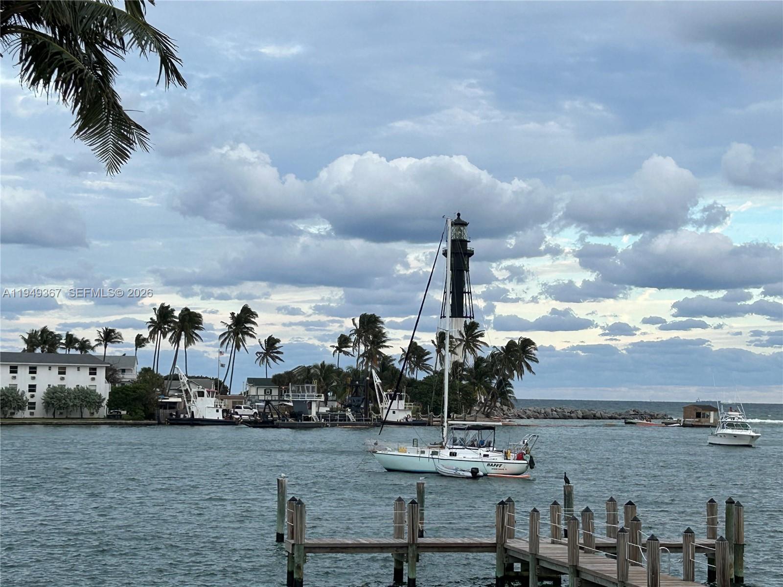 A sailboat floats in a harbor near a lighthouse, palm trees, and a wooden dock — 2508 Bay Dr # 12, Pompano Beach FL 33062, POMPANO BEACH, FL