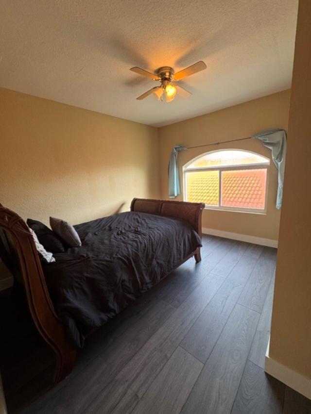 A bedroom with dark wood flooring, a wooden bed frame, and an arched window — 1033 Grove Park Circle, Boynton Beach FL 33436, BOYNTON BEACH, FL
