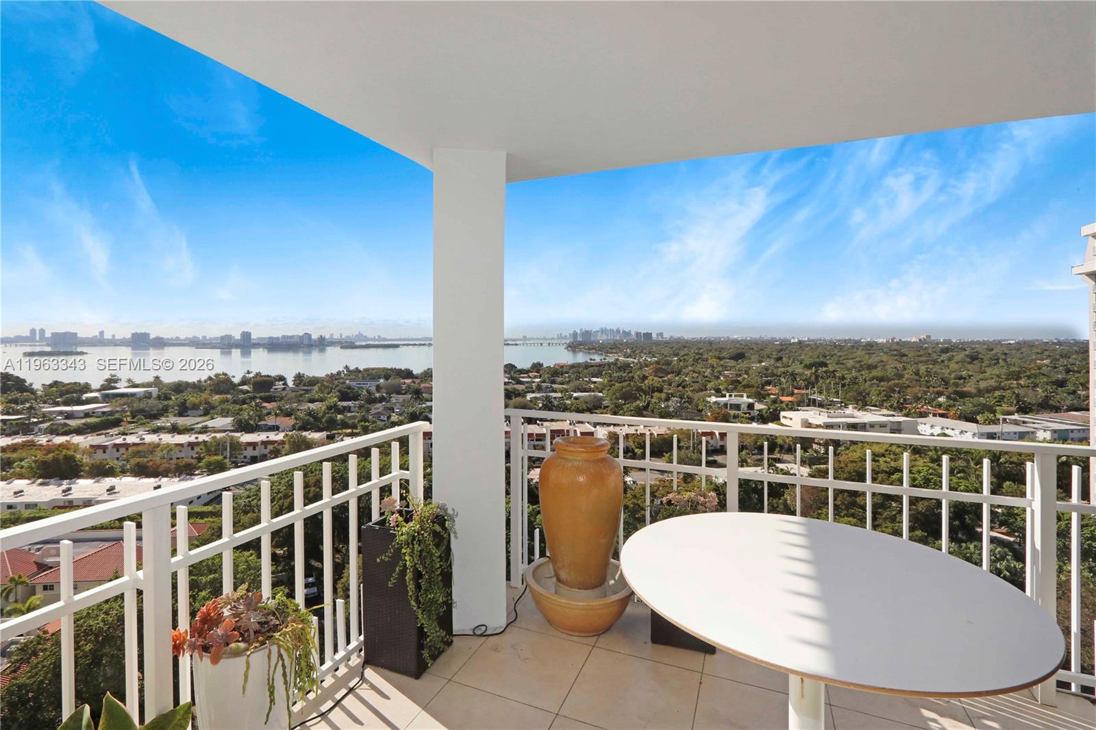 A balcony with a white table, a large decorative vase, and a panoramic water view — 1000 Quayside Ter # 1608, Miami FL 33138, MIAMI, FL