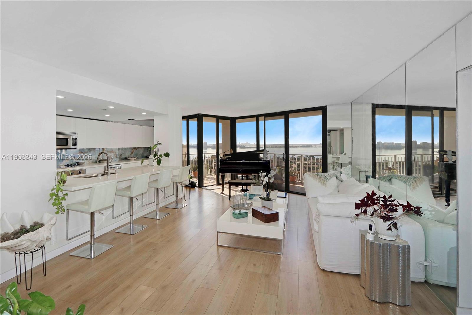 A modern open-concept living room features a kitchen island, piano, and floor-to-ceiling windows — 1000 Quayside Ter # 1608, Miami FL 33138, MIAMI, FL